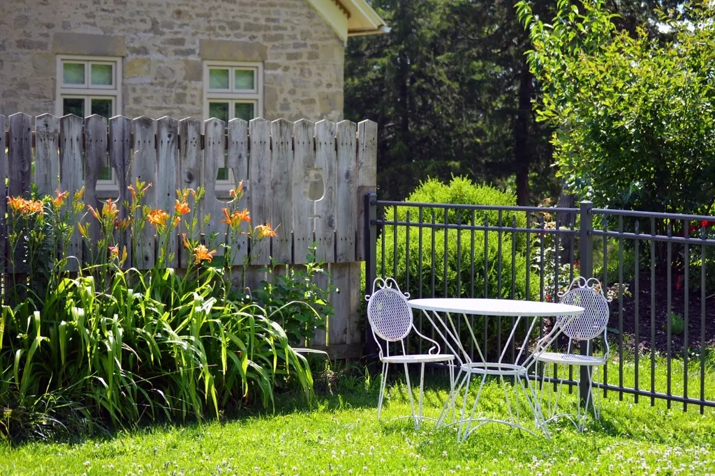 Stone cottage garden with a lawn, flower beds and a picket fence